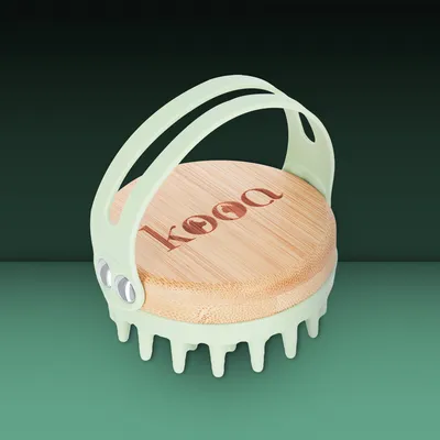 Brosse avec manche en plastique vert clair, base ronde en bois gravée « kooa », picots souples visibles dessous.