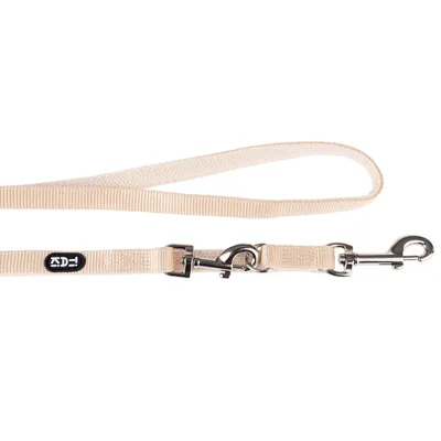 Beige Hundeleine mit Metallkarabiner und schwarzem Logoaufnäher. Verstellbare Länge, robustes Material.