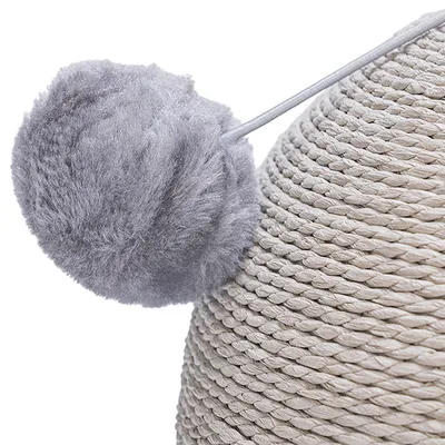 Detaljevisning af en grå plysbold på en elastisk snor, fastgjort til et kradsetræ af flettet rebmateriale.