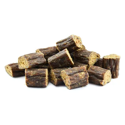 Morceaux cylindriques de friandises brunes pour animaux, sans emballage ni marque visible, présentés en tas sur fond blanc.
