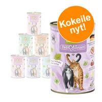 DeliCATessen kissan märkäruokapurkkeja, etiketissä kaksi kissaa. Etualalla purkki: Lamb & Turkey, Paté. Oranssi ympyrä tekstillä 'Kokeile nyt!'.