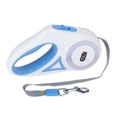 Laisse rétractable Tiaki blanche et bleue avec poignée, bouton de verrouillage visible et sangle grise munie d’un mousqueton métallique.