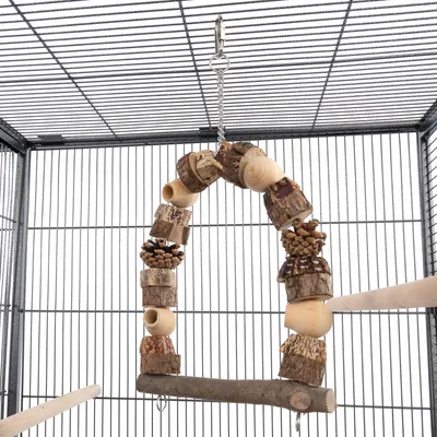 Jouet suspendu en bois naturel avec pommes de pin et perchoir, accroché à une chaîne métallique dans une cage pour oiseaux ou petits animaux. Matériaux visibles : bois, métal.