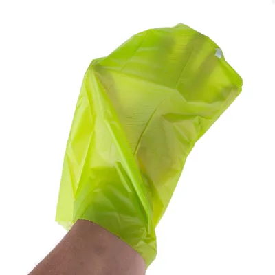 Hand med en gul plastpåse pådragen, visar användning av påsen som skydd eller täckning.