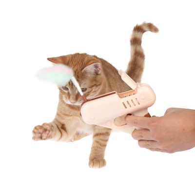 Juguete para gatos con dispositivo manual y accesorio de plumas, el gato interactúa activamente con el juguete.