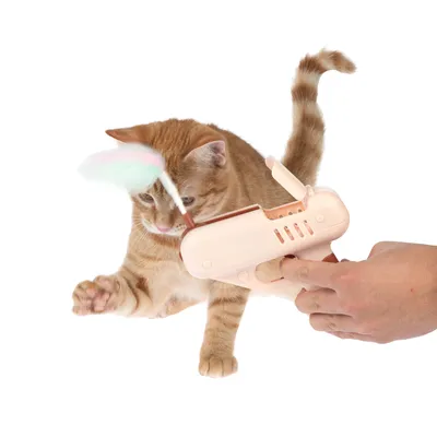 Juguete para gatos con dispositivo manual y accesorio de plumas, el gato interactúa activamente con el juguete.