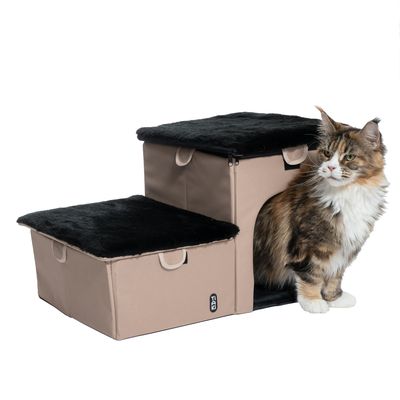 Escalier pour animaux en tissu beige avec deux marches à surface noire, compartiment intérieur visible, chat assis à côté. Étiquette TIAKI sur le devant.