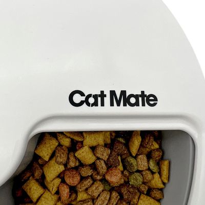 Cat Mate distributore automatico di cibo riempito con cibo secco, nome del marchio visibile su corpo bianco.