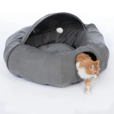 Grey cat bed with cave shape, soft inner cushion and toy ball. Cat exits the bed through a side entrance.