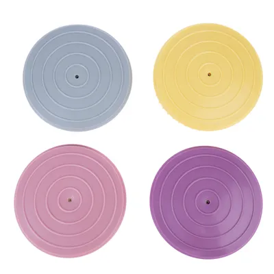 Quatre couvercles ronds en plastique, couleurs bleu clair, jaune, rose et violet, avec cercles concentriques visibles au centre de chaque couvercle.