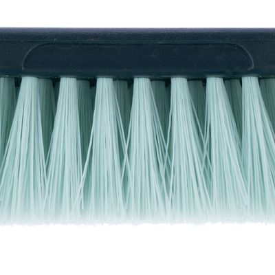 Близък план на светлозелени пластмасови влакна на четка с черна дръжка.