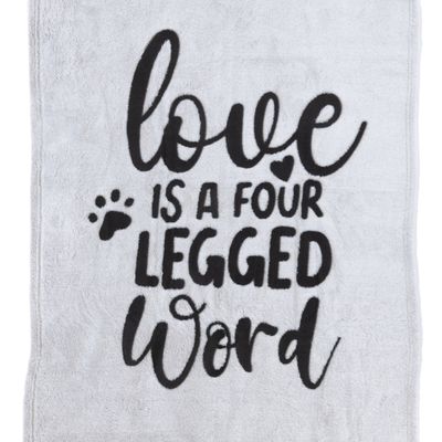 Testo su tessuto grigio: "Love is a four legged word" con impronta di zampa e simbolo a forma di cuore.