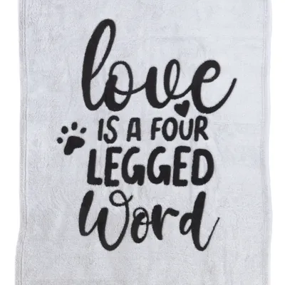Testo su tessuto grigio: "Love is a four legged word" con impronta di zampa e simbolo a forma di cuore.