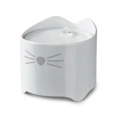 Fontaine à eau en céramique blanche, forme de tête de chat avec motif museau et moustaches, jet d’eau visible au centre du couvercle.