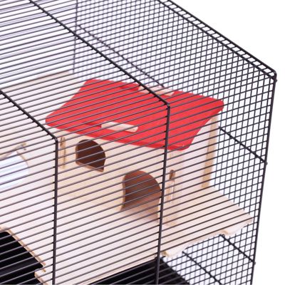 Trähus med rött tak och två ingångar, omgiven av en bur av metallgaller.