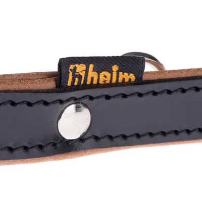 Nahaufnahme eines schwarzen Lederhalsbands mit sichtbarem Heim-Logo und Metallniete.