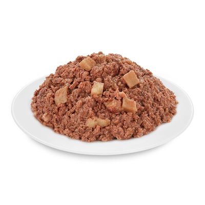 Apróra vágott, barna színű nedves állateledel darabokkal fehér tányéron, csomagolás nélkül látható.