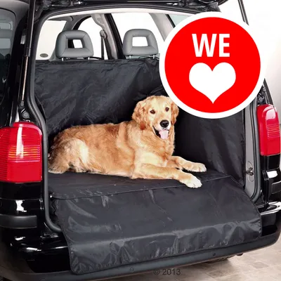 Cane sdraiato su copertura protettiva nera per bagagliaio auto, materiale tessuto visibile. Cerchio rosso con testo bianco 'WE' e cuore stilizzato in alto a destra.
