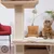 Arranhador para gatos em sisal com plataforma almofadada e bola pendurada. Gato tigrado ao lado da estrutura.