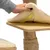 Mano che mostra un cuscino rimovibile e imbottito con chiusura a strappo su una piattaforma in legno di un tiragraffi.