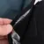 Close-up showing a hand opening a black fabric fastener to reveal a silver reflective inner lining and hook-and-loop closure.