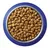 Bowl filled with round brown dry pet food kibble, viewed from above. Blue and silver metal bowl visible. No brand or text shown.