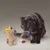 Graue Katze neben einem Plüschspielzeug in Form eines gelben Lamas mit Schwanz aus buntem Stoff. Spielzeug für Haustiere.