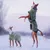 Deux chiens à poil court portant des manteaux verts Hurtta, l’un debout sur ses pattes arrière, l’autre marchant dans la neige. Marque Hurtta visible sur le manteau.