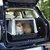 Transportbox aus Kunststoff mit Metallgitter, im Kofferraum eines Autos platziert. Geeignet für sichere Tierbeförderung.