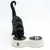 Black cat eating from a white double bowl with stainless steel inserts. The 'Taki' logo is visible on the bowl.