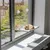 Hamac pour chat fixé à une fenêtre par ventouses, avec un chat roux couché dessus. Structure en tissu et cordes visibles, installation sur vitre intérieure.