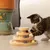 Katze spielt mit einem Holzspielzeug mit mehreren Ebenen und bunten Kugeln.
