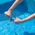 Hände wringen ein blaues Reinigungstuch über einem Pool aus, Wasser tropft ins Becken.