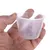 Målebæger af transparent plast med skala i milliliter og cups, maksimal kapacitet 160 ml. Bægeret holdes af en hånd.