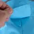 Gros plan sur une main soulevant un rabat en tissu bleu avec couture visible, montrant le détail de la fermeture d’un vêtement ou accessoire pour animal.