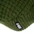 Gros plan sur un tricot vert avec étiquette visible portant le nom de la marque TIAKI.