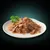 Chunks of meat in gravy served on a white plate with a garnish of parsley, showing the texture and appearance of the wet pet food product.