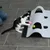 Chat noir et blanc jouant avec une balle rose devant un tapis d’activité gris à ouvertures, balle jaune visible sous le tapis. Sol carrelé gris, personne assise partiellement visible.