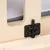 Detailansicht eines schwarzen Metallverschlusses an einer Holzkonstruktion mit grauem Stoff im Hintergrund.