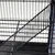 Vue rapprochée d'une cage en métal noir avec grille et plateau inférieur visible, sans marque ni texte apparent.