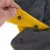 Gros plan sur une main tenant un tissu gris et jaune avec boutons-pression visibles, matière polaire. Montre le système de fermeture du produit.