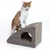 Brown scratching box with round entrance and slanted surface, demonstrated by a red and white cat.