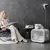 White cats in and on a modern white pet house with ventilation, next to a seated person in a stylish room.