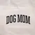 Inscripción "DOG MOM" sobre tela beige.