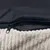 Close-up of a zip on a black fabric cover with a soft, ribbed beige surface.