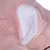 Detailopname van roze pluche materiaal met witte voering, mogelijk onderdeel van een dierenaccessoire.