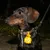 Hund mit braunem Halsband und gelbem Anhänger in Form eines Cartoon-Tiers, befestigt an der Leine. Nachtaufnahme im Garten.