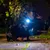 Chien avec harnais et laisse, portant une lumière LED allumée au collier lors d’une promenade nocturne. Lumière blanche visible sur le cou du chien.