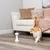 White laser toy with two red light beams on wooden floor, next to a cat in a living room with sofa and cushions.