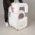 Person demonstrating assembly of a white kooa cat toilet with removable lid and round inner chamber. Wooden legs and controls visible.